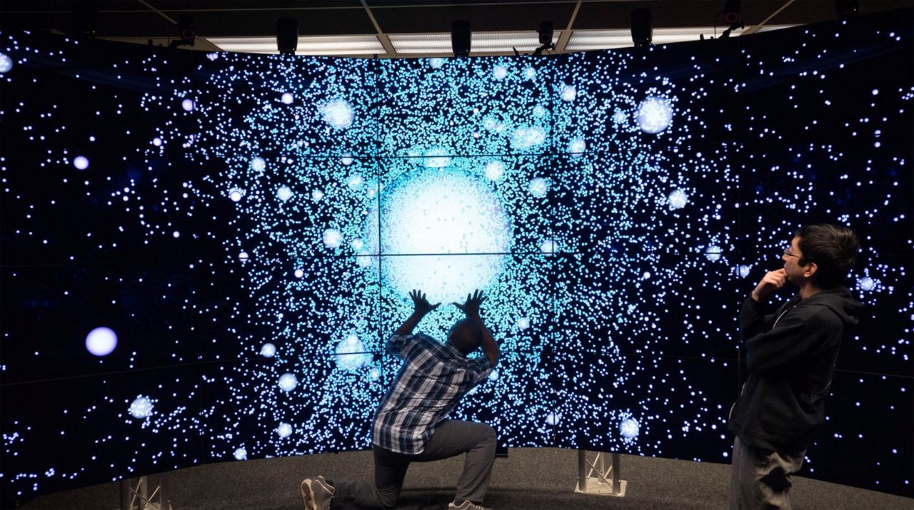 Young researchers examine, as a group, large scale cosmology data in CAVE2.
